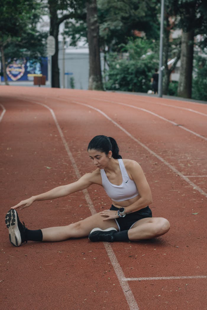 Athletic woman stretching on a running track, preparing for workout session.