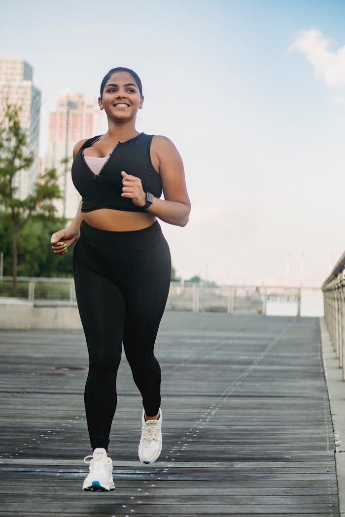 Smiling woman jogging on a city boardwalk, embodying a healthy lifestyle.